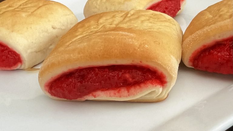 Homemade Burikat bread with bright red pudding filling on a white plate