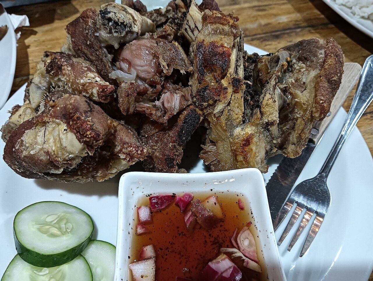 Crispy Pata: Filipino Fried Pork Leg with Vinegar Dip - Deep fried pork pata served with vinegar and cucumber slices.